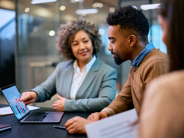 trainer looks on at apprentice at laptop